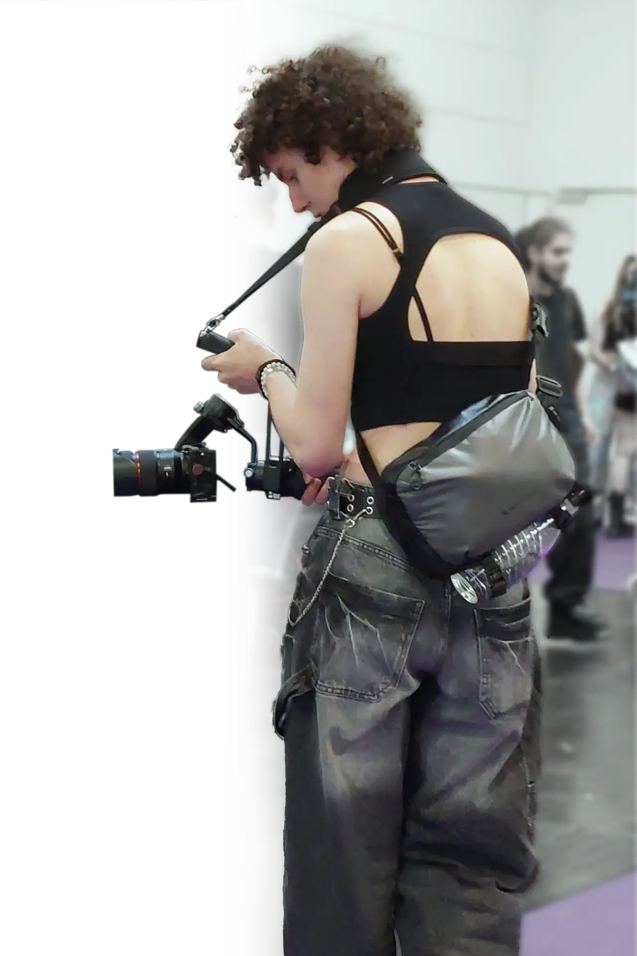 The Picture shows the Owner of the website, Melly, as she is filming a car with her gimbal and camera. She is creating the flow by slowing moving around the automotive opject. She is looking down onto the screen of the camera.